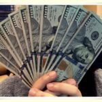 person carefully counting cash on tight minimum wage budget